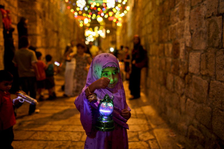 FILE - In this Tuesday, Aug. 10, 2010 file photo, a young Palestinian Muslim girl walks in an alley of Jerusalem's old city holding a traditional Ramadan lantern while celebrating with other children the announcing of the holy month of Ramadan. Millions of Muslims around the world will mark the start of Ramadan on Thursday, June 18, 2015 a month of intense prayer, dawn-to-dusk fasting and nightly feasts. (AP Photo/Muhammed Muheisen, File)